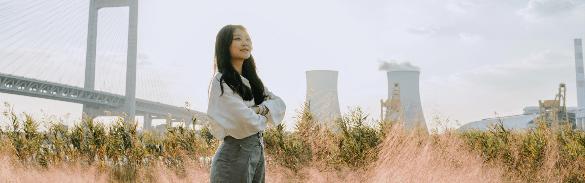 A woman standing in a field of tall grass under the clear blue sky.