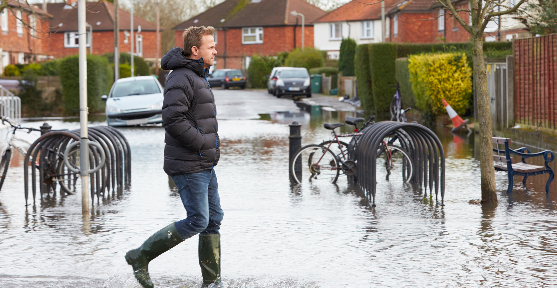 Man loopt met regenlaarsen aan in ondergelopen staat.