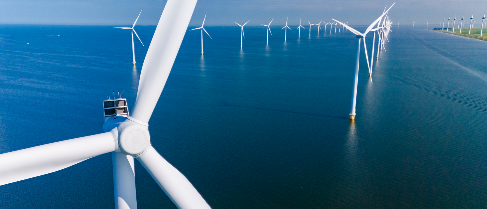  A large tower equipped with wind turbines stands beside a boat on calm waters, showcasing renewable energy in action.