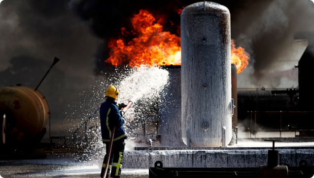 Fire fighter spraying foam on fire.