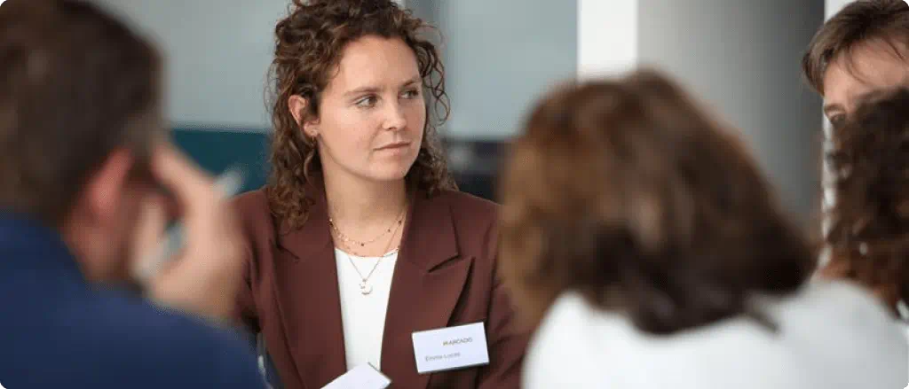 A woman in a business suit engages in conversation with colleagues in a professional setting.