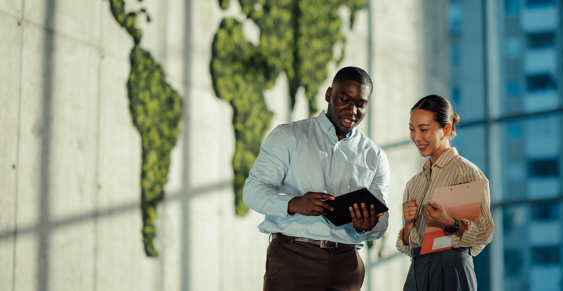  A pair of individuals pose in front of a wall adorned with a globe, suggesting a global theme.