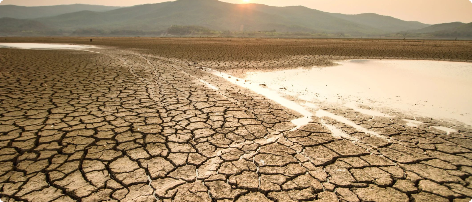 The sun sets over a drought-stricken lake bed.