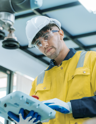  A man in a white protective suit and mask is focused on his work while using a laptop.
