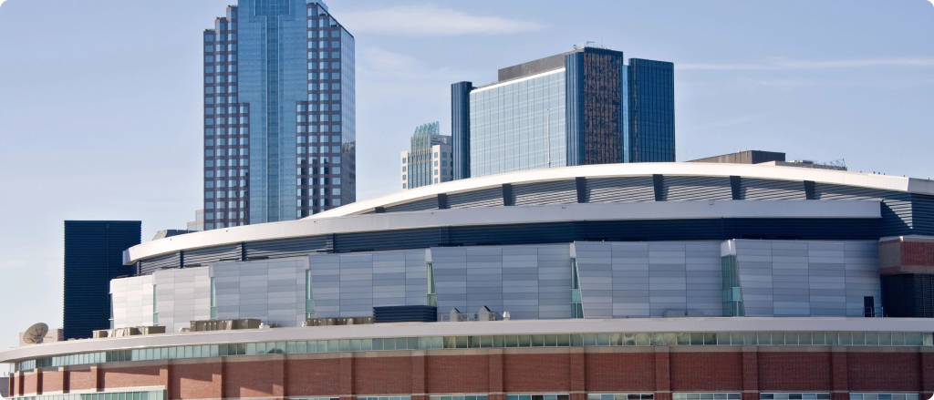 A large building with a prominent tall tower rising in the background against a clear sky.