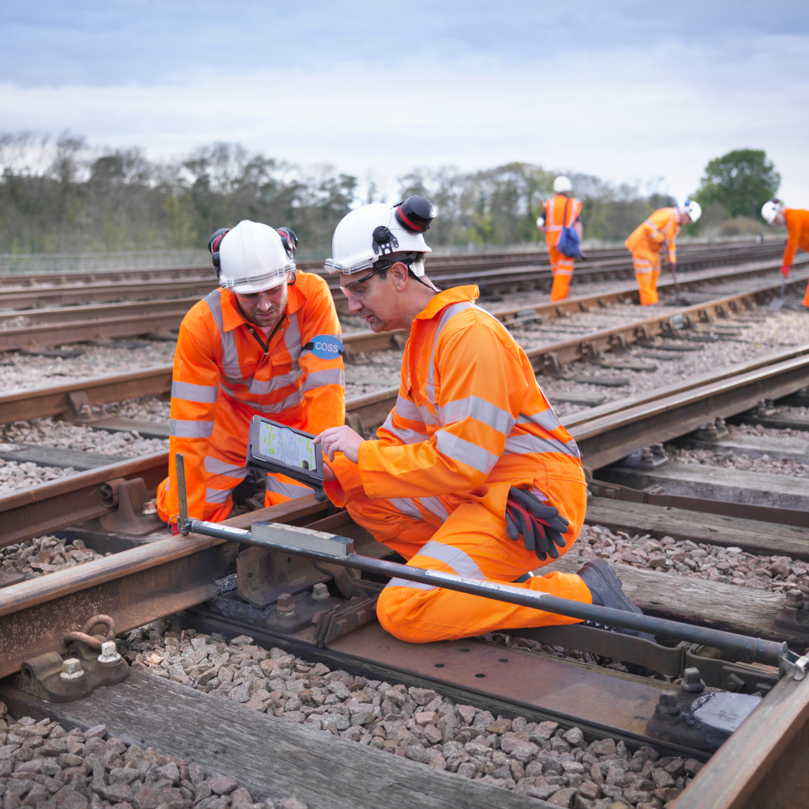 People wearing safety gears, inspecting the train tracks.