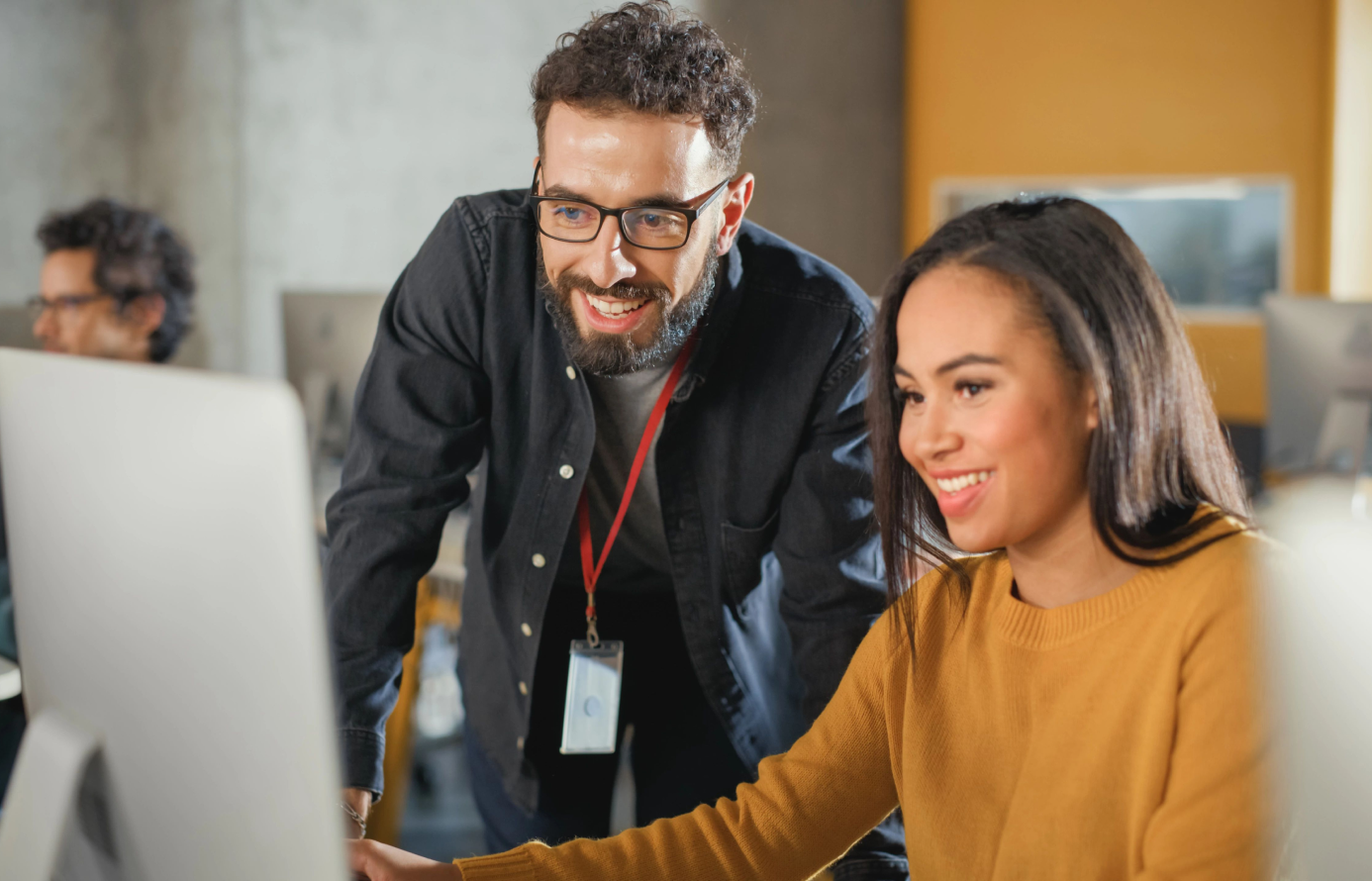 Smiling man and woman engaged in computer work.