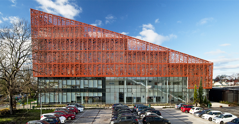 A triangular-shaped building constructed from red metal, showcasing a modern architectural design.