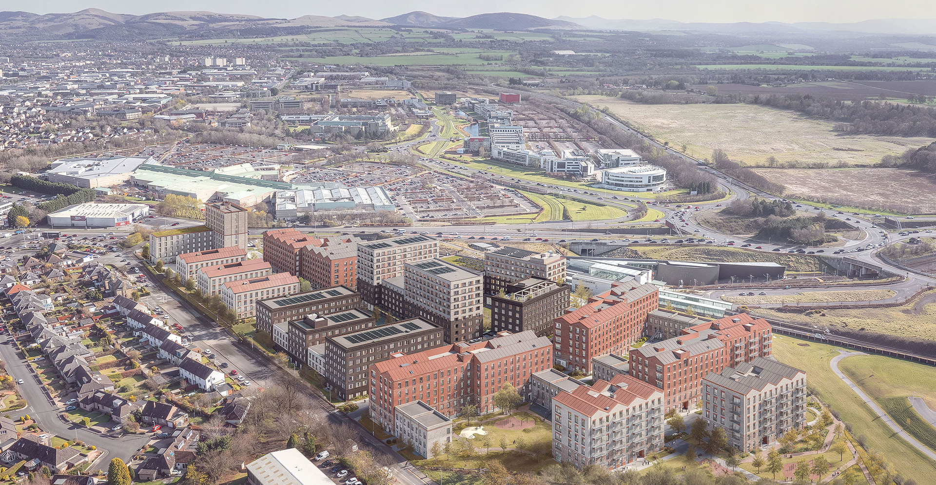 Aerial view of a city featuring various buildings and surrounding hills under a clear blue sky.