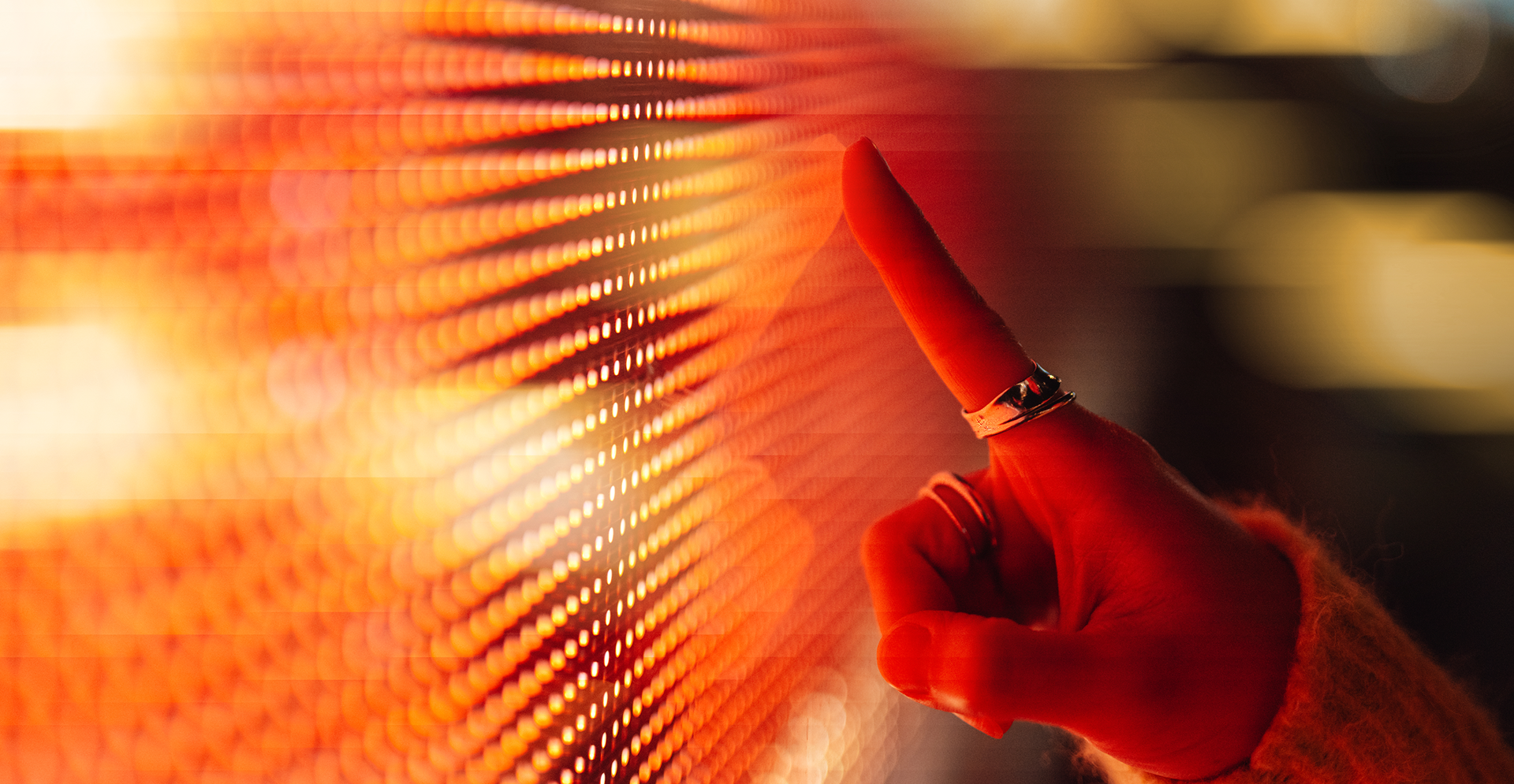 A hand is raised, with a finger pointing at a vivid red screen, suggesting focus on the content displayed.