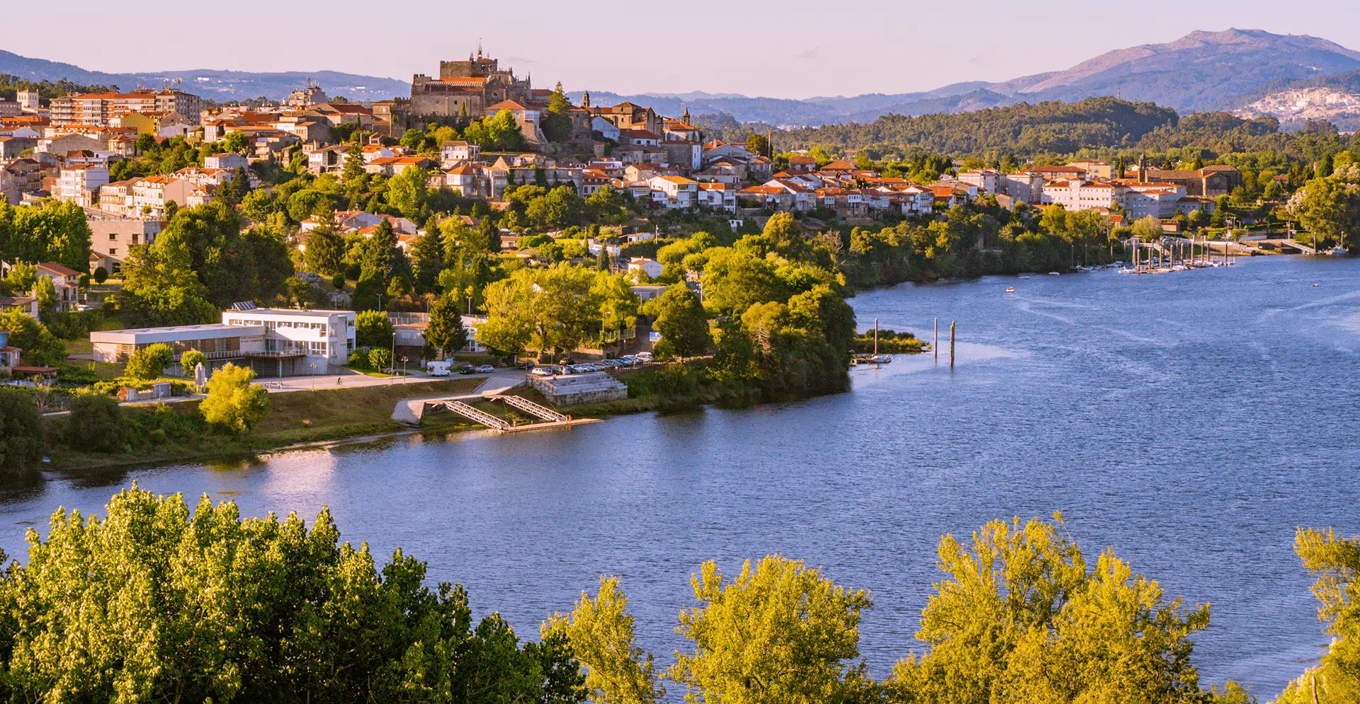 A serene body of water reflecting the sky, surrounded by lush greenery and distant hills.