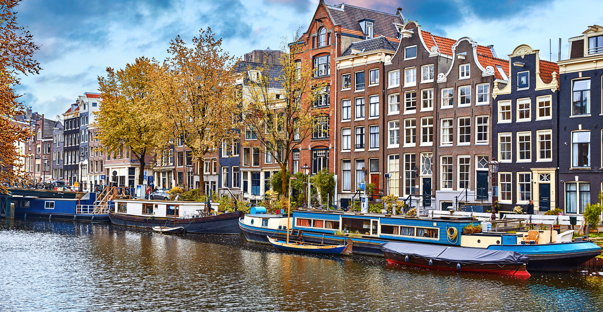 A scenic canal lined with buildings, featuring several boats gently floating on the water's surface.