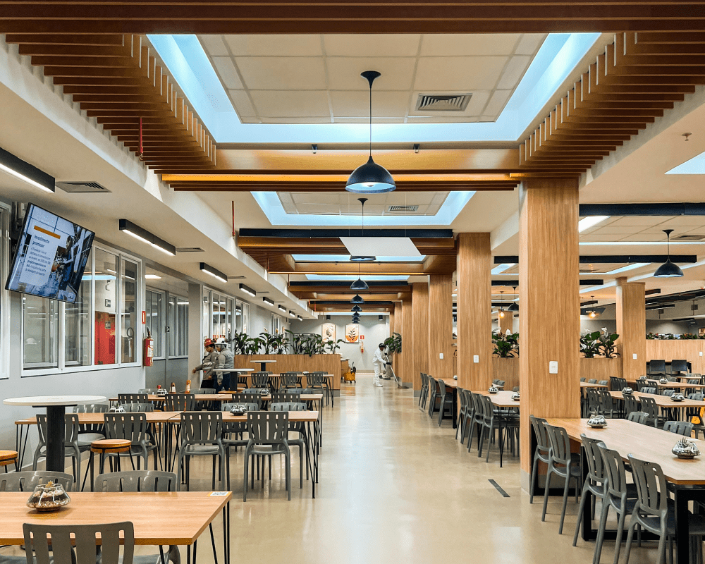 Interior of a spacious cafeteria with wooden tables and chairs.