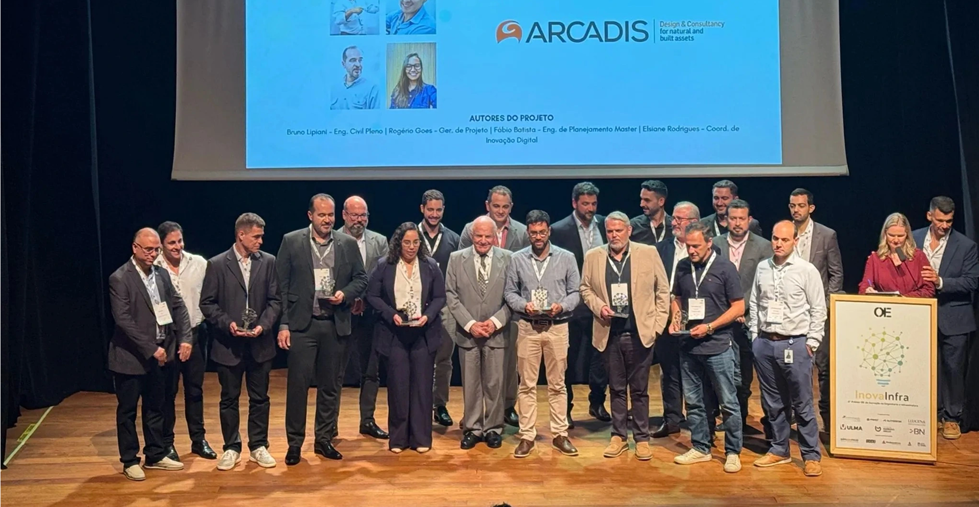 A group of people on stage proudly holding their awards, smiling and celebrating their achievements together.