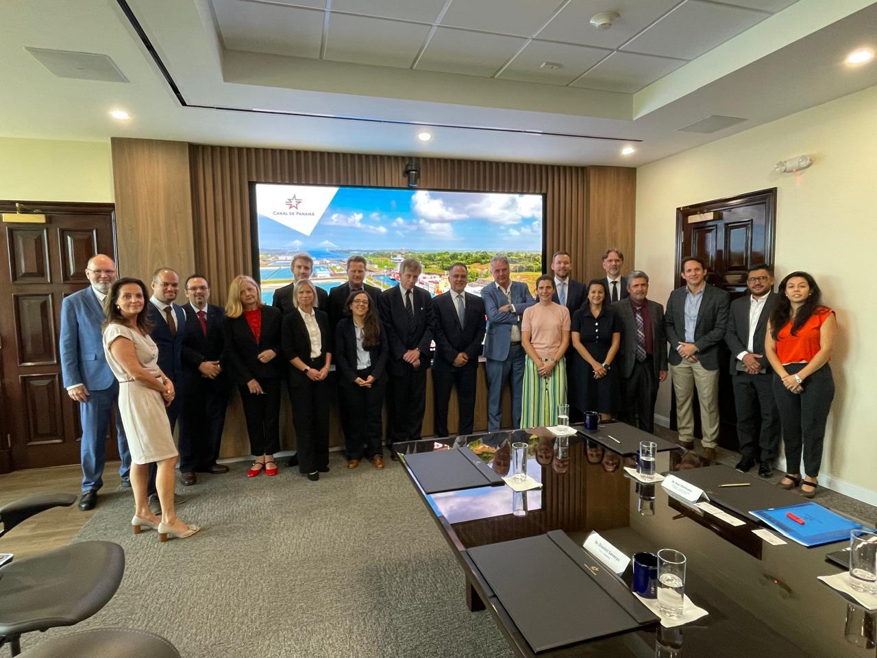 A group of people stands together in front of a large screen displaying information or visuals.