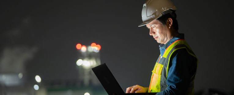 Asian programmer working on laptop at night