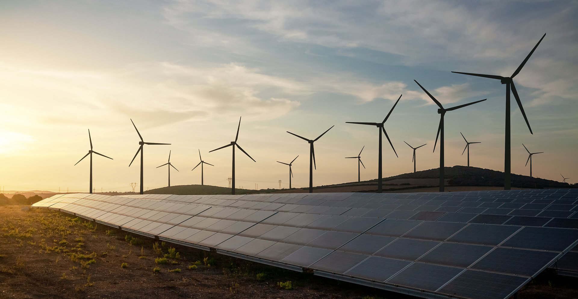Solar panels and wind turbines silhouetted against a vibrant sunset sky, highlighting renewable energy sources.