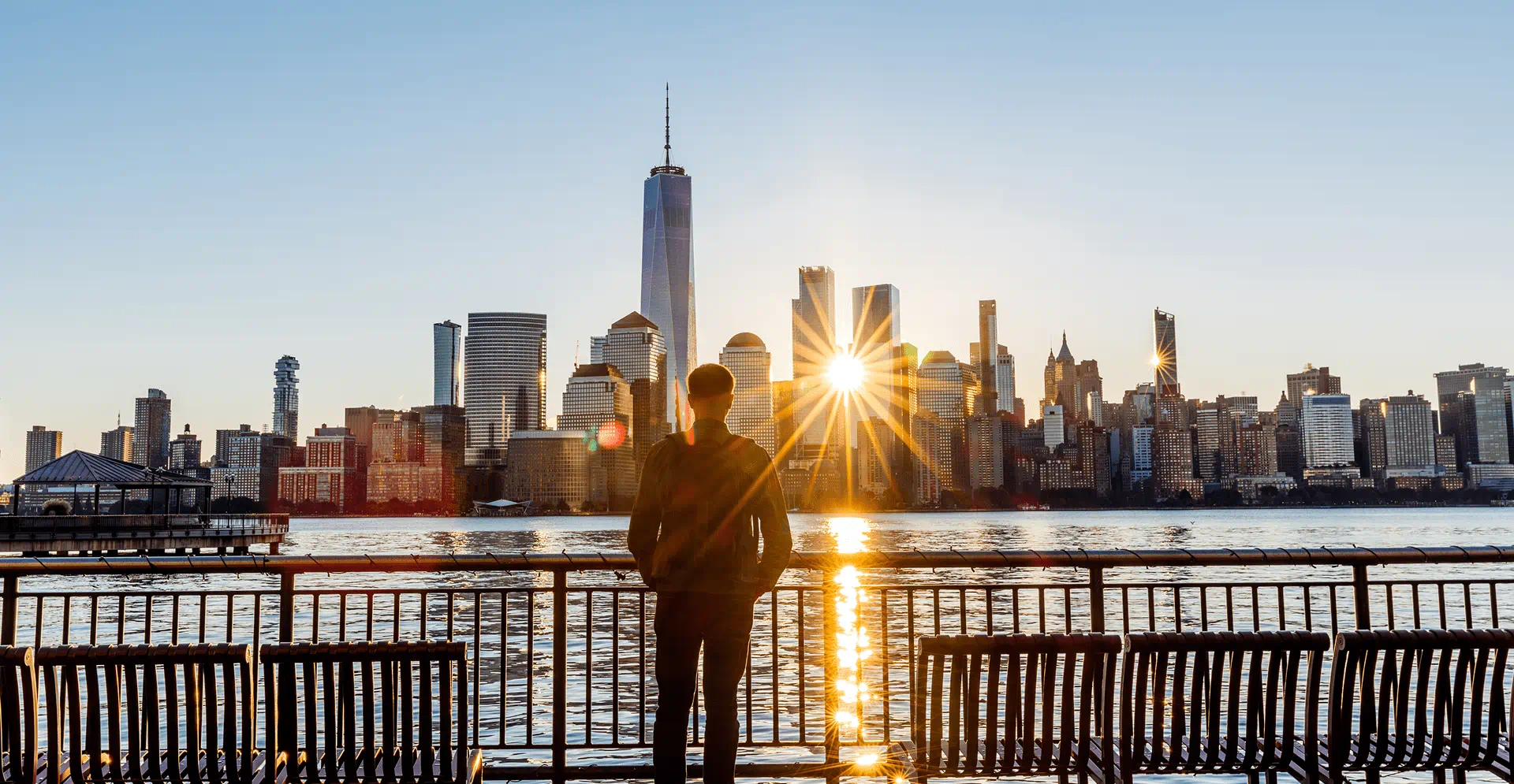 Rear view of a man looking at New York City skyline at sunrise, USA