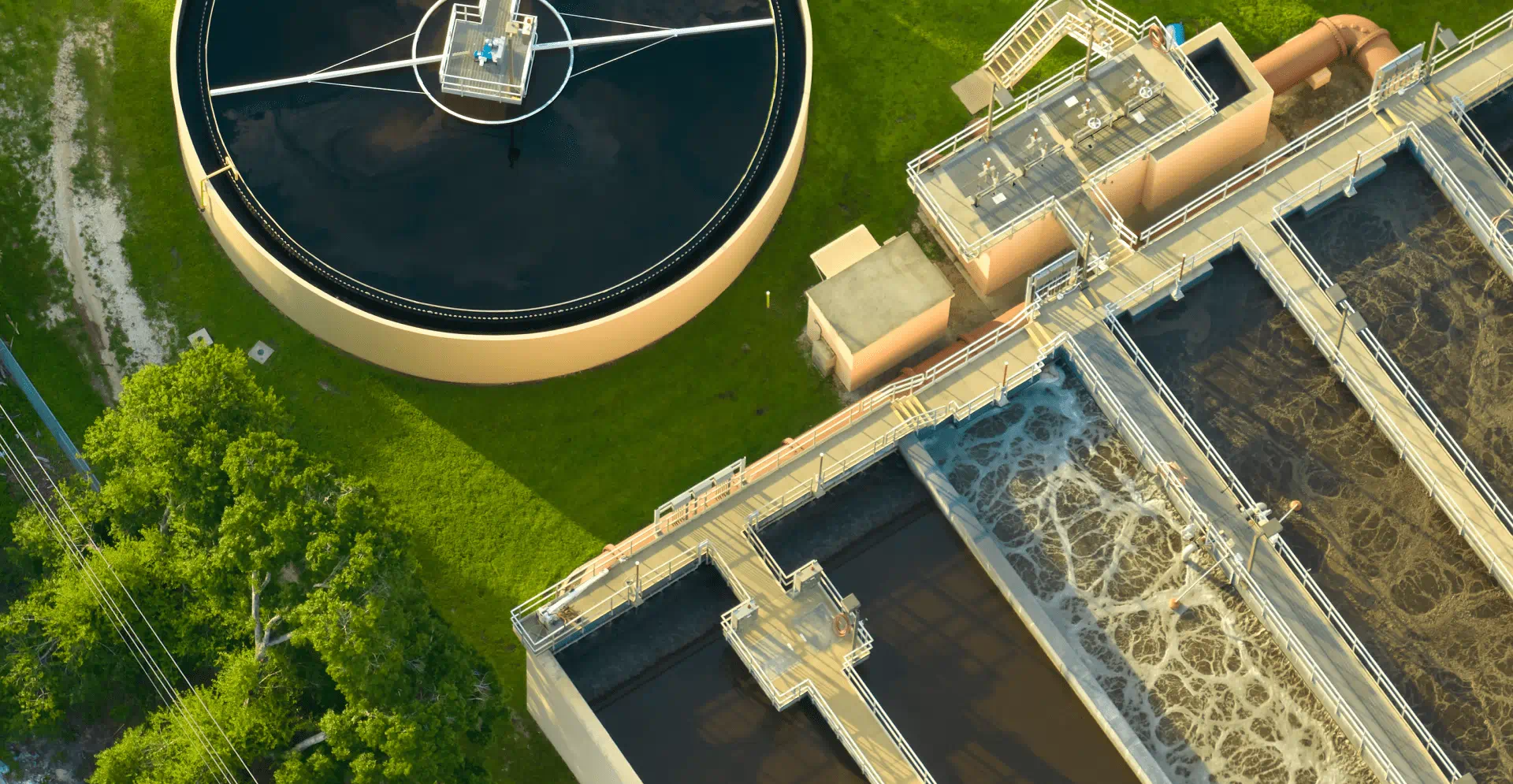Aerial view of a water treatment plant showcasing large tanks and filtration systems surrounded by greenery.
