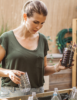 Circulaire oplossingen voor minder CO2-uitstoot die bijdragen aan een circulaire economie Vrouw die lege plastic fles hergebruikt als circulaire oplossingen voor minder CO2-uitstoot en zo een bijdrage levert aan een meer circulaire economie