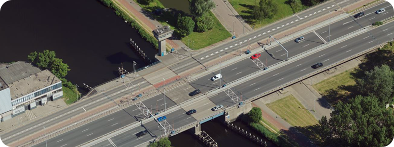  An aerial perspective of a bridge crossing a river, highlighting the flowing water and natural landscape surrounding it.