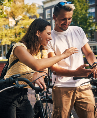 Young couple with a smartphone while exploring the city of Amsterdam by bike