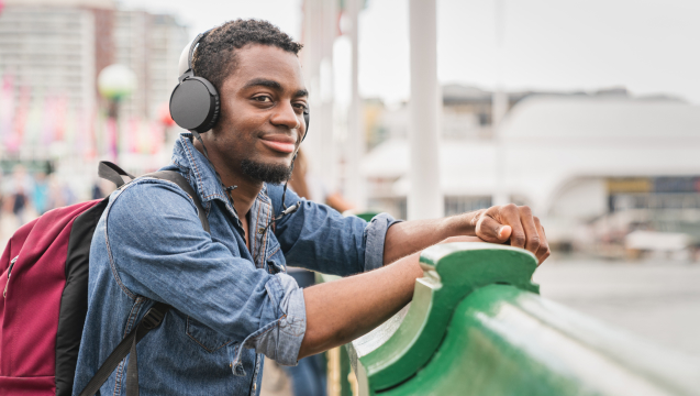 Young tourist leaning against the Pyrmont bridge with headphones on