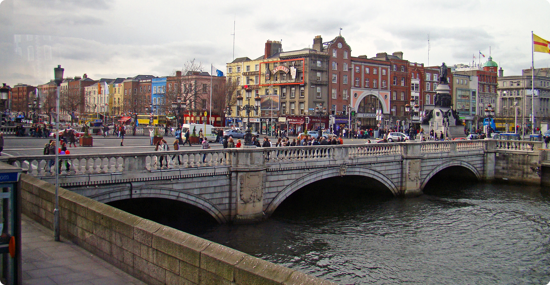 A scenic bridge spans a river, connecting two banks under a clear blue sky.
