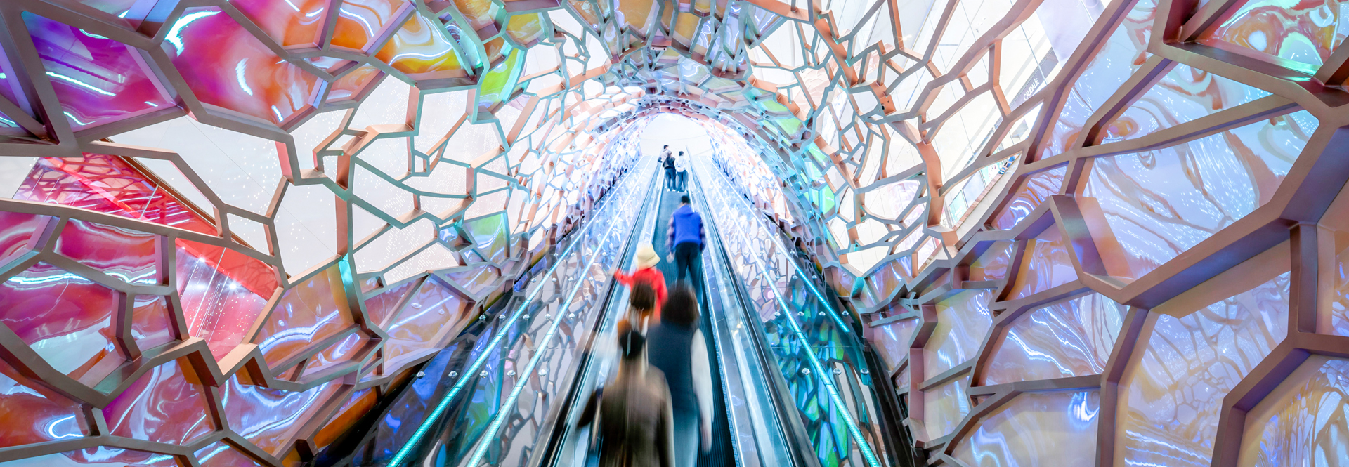 A vibrant tunnel filled with colors, featuring people walking through, creating a lively and dynamic atmosphere.