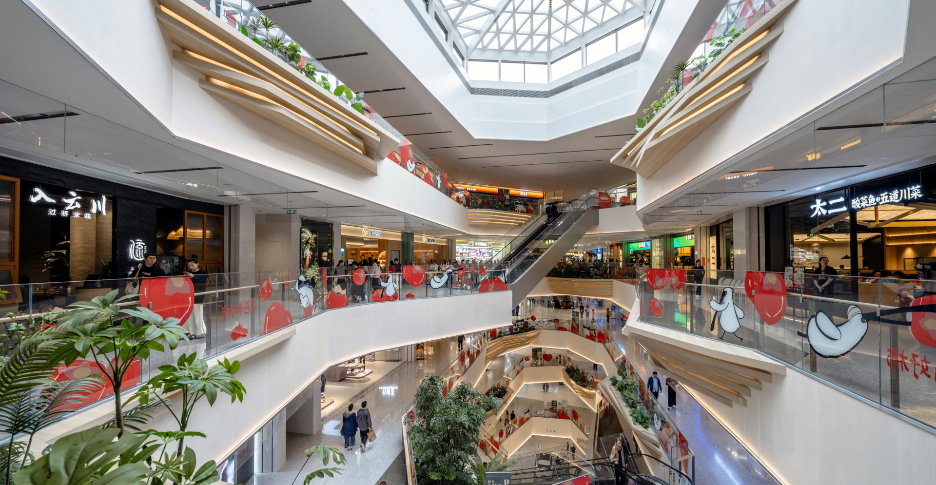 A bustling shopping mall interior filled with people walking and browsing various stores.