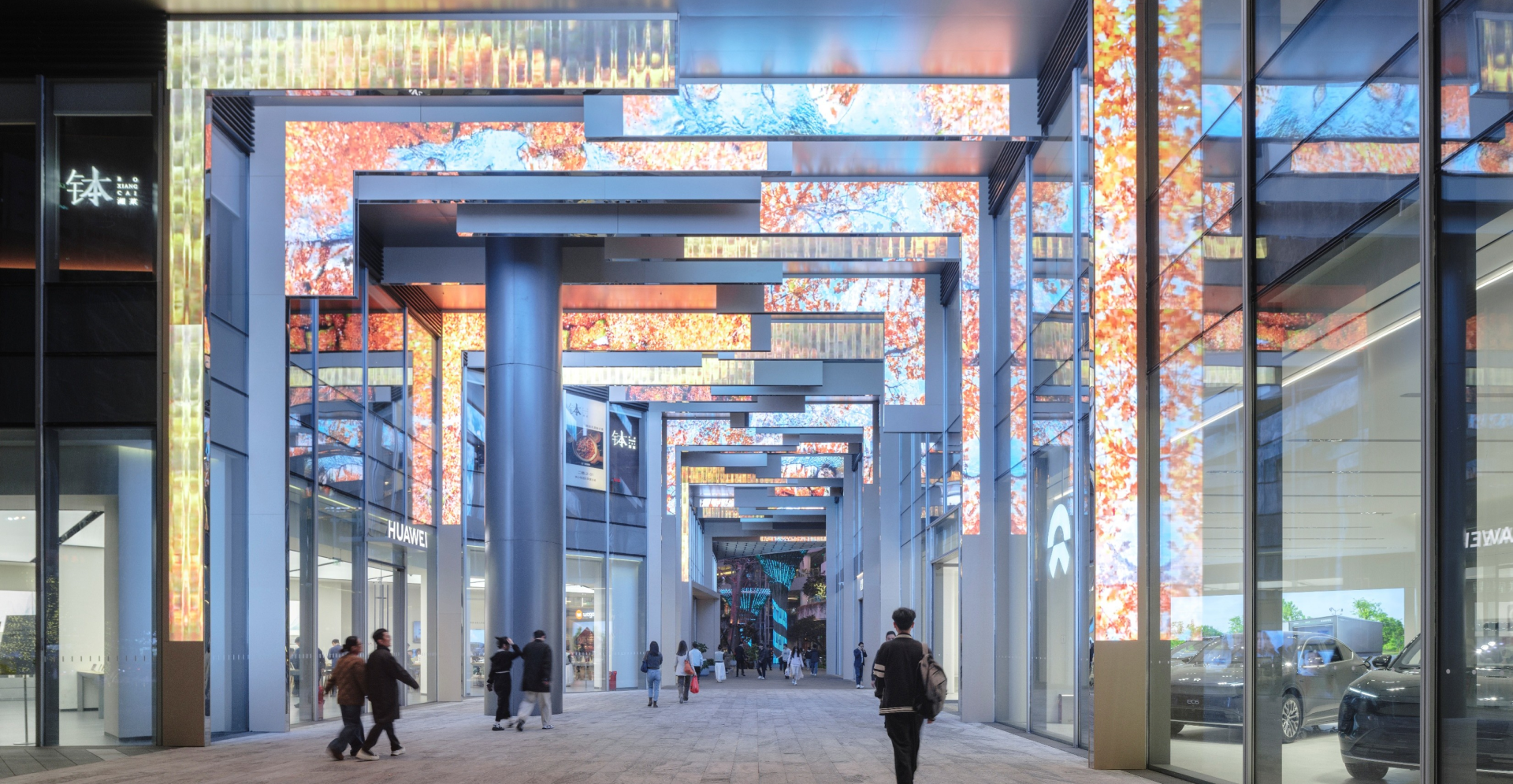 People stroll through a vibrant mall illuminated by colorful lights, creating a lively and festive atmosphere.
