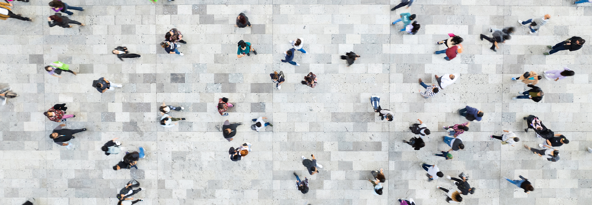 Aerial perspective of individuals strolling on a sidewalk, illustrating the vibrancy and activity of a city environment.