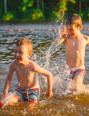 Betere waterkwaliteit dankzij ijzerzand Twee jongens rennen elkaar in het water achterna.