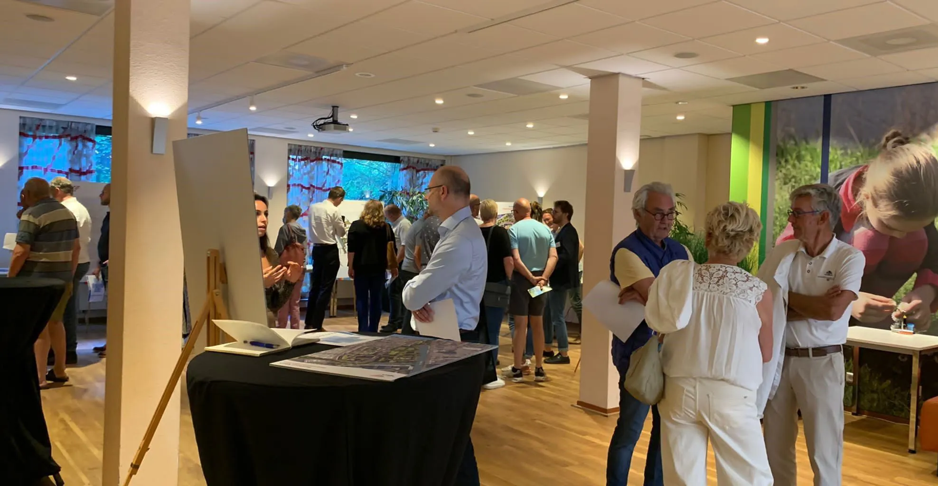 People gathered in room with colorful mural in background.