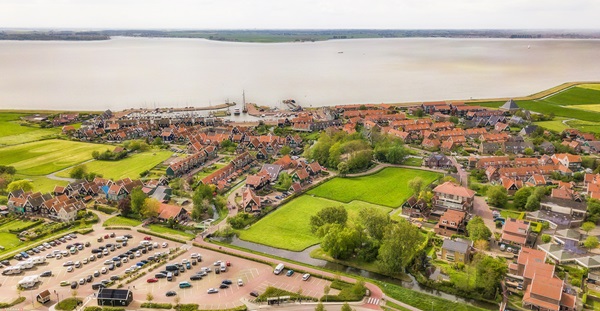 Duurzame versterking van de Markermeerdijken Luchtfoto van deel van de  Markermeerdijken met dorpje aan het water.