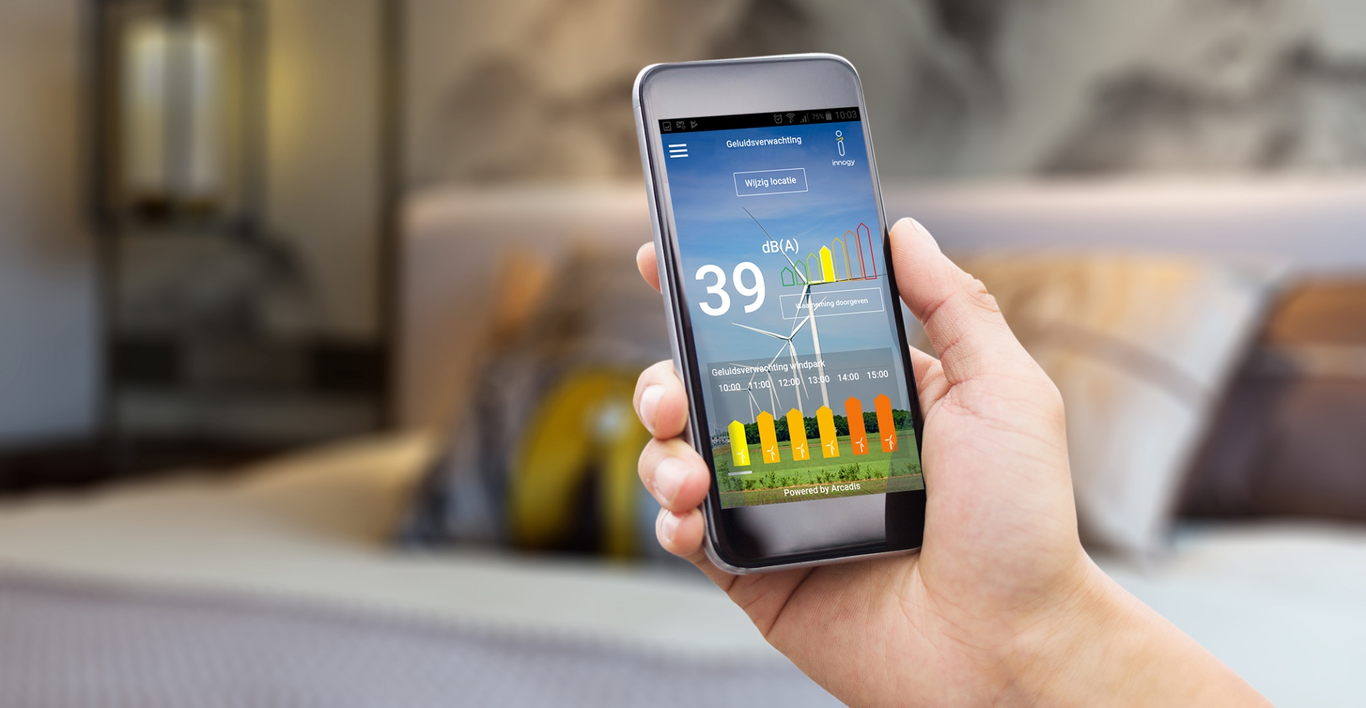 Iemand die een smartphone vasthoudt met daarop een app over windverwachting bij windturbines