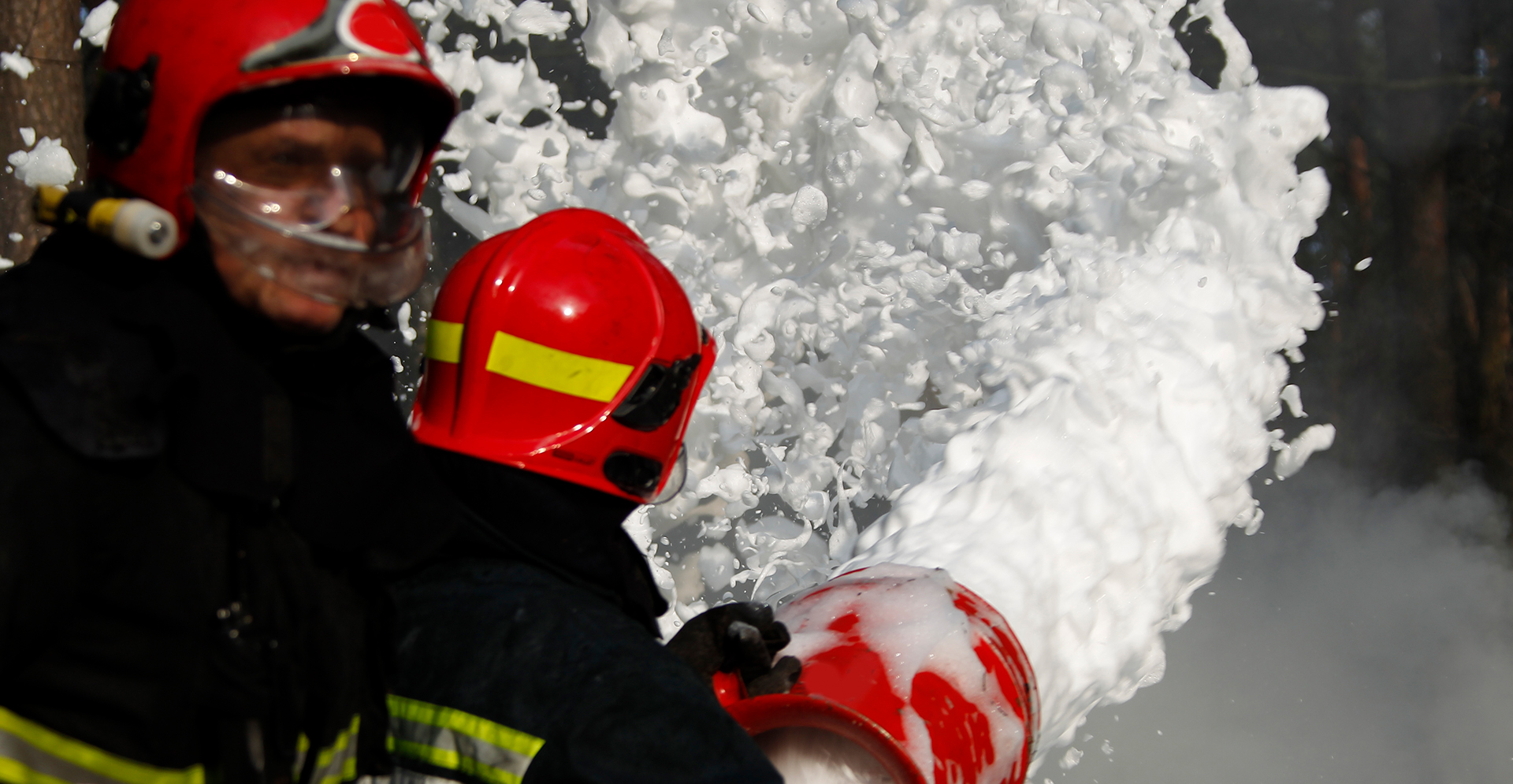Brandweermannen die blussen met schuim