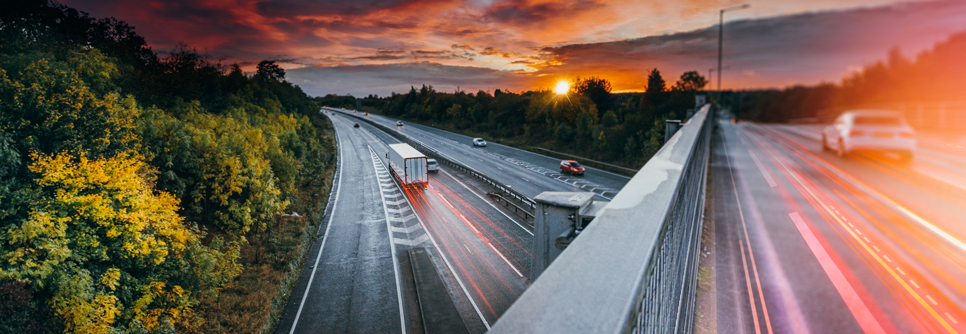 Sunset over a highway, showcasing cars in motion against a backdrop of warm, glowing hues.