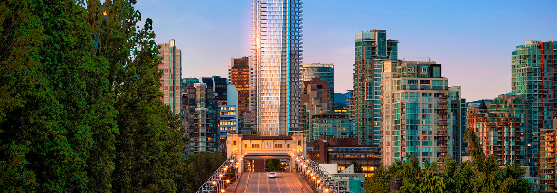 A city bridge connects two sides, with towering buildings visible in the background against the skyline.