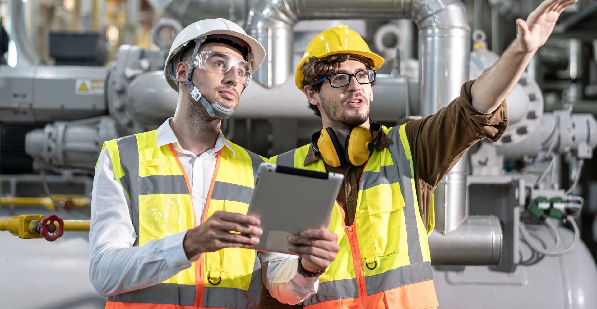 Two men working together wearing a protective hard hat and eye glasses.